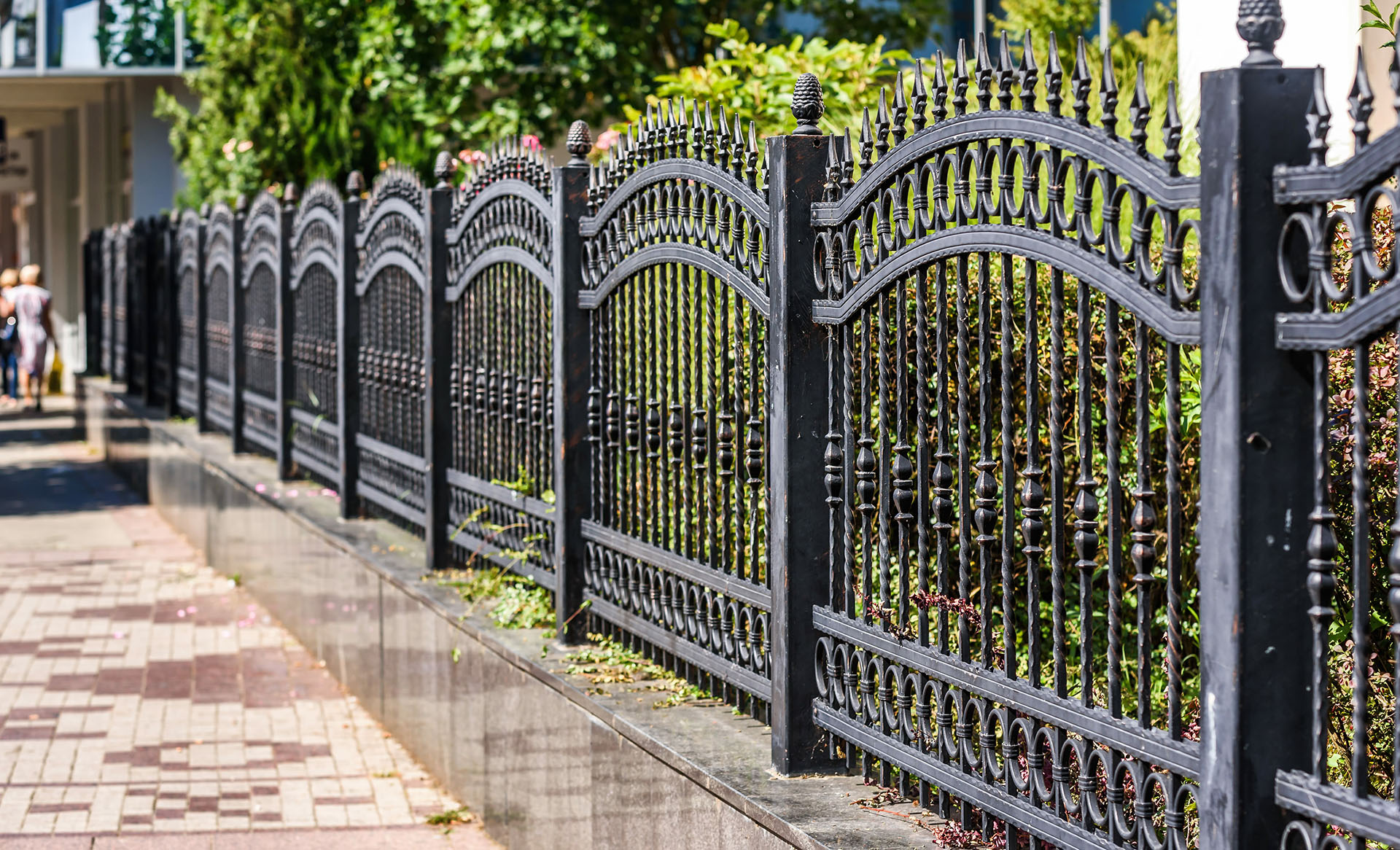 An iron fence by a sidewalk