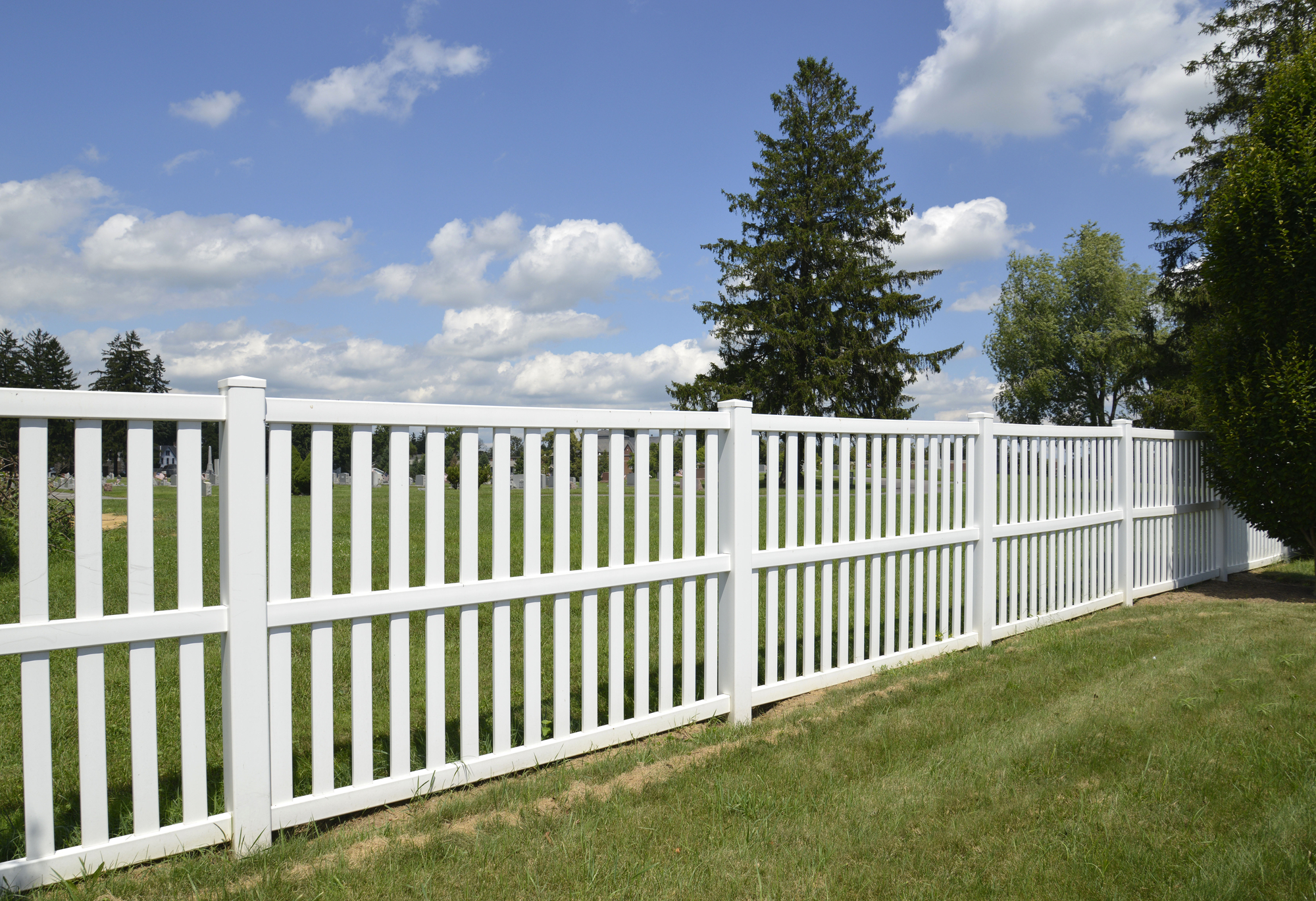 White vinyl fence by green lawn