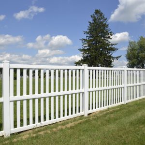 White vinyl fence by green lawn
