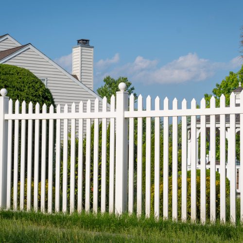 A white vinyl picket fence complementing a well-landscaped backyard